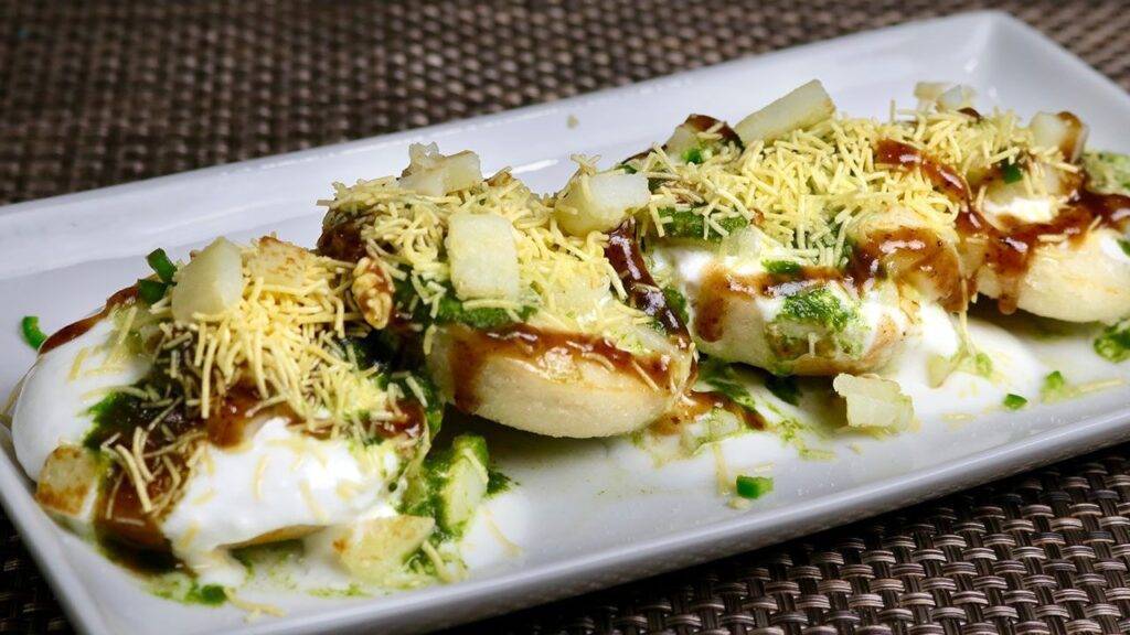 A plate of Idli Chaat garnished with sev, diced potatoes, chutneys, and yogurt, creating a colorful and appetizing Indian street food dish.