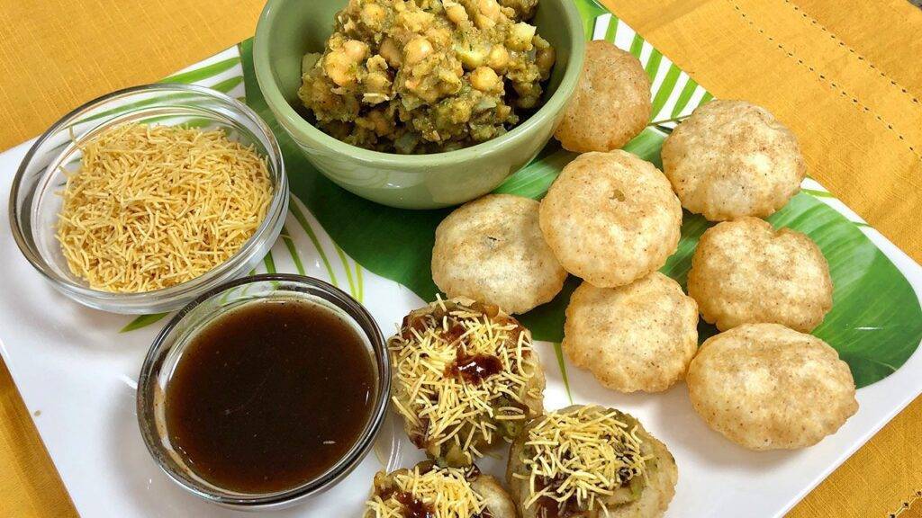 A plate of Ragda Puri Chaat with crispy puris, spiced chickpea mixture, sev, and tamarind chutney.